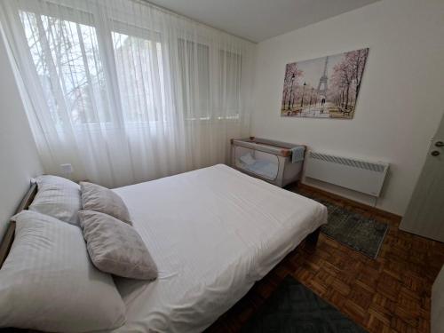 a bedroom with a white bed and a window at Luna apartman in Čačak