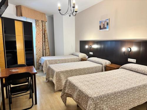 a hotel room with four beds and a table at Hostal La Isla in Montijo