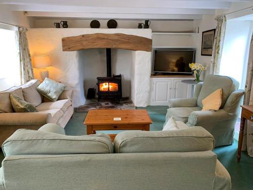 a living room with couches and a fire place at Condurrow Cottage in Saint Anthony