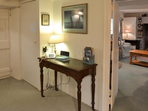 a room with a desk with a phone and a lamp at Condurrow Cottage in Saint Anthony