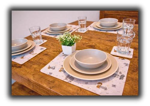 a wooden table with plates and glasses and a bowl at Pitchside House Walk to Anfield sleeps 7 in Liverpool