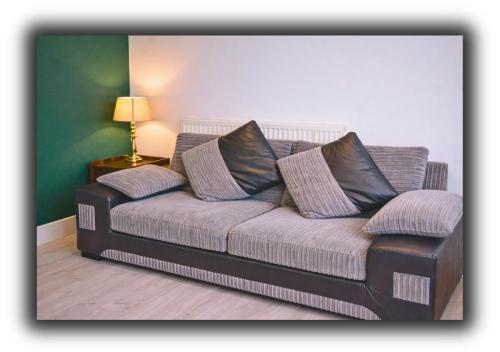 a couch with two pillows on it in a room at Pitchside House Walk to Anfield sleeps 7 in Liverpool