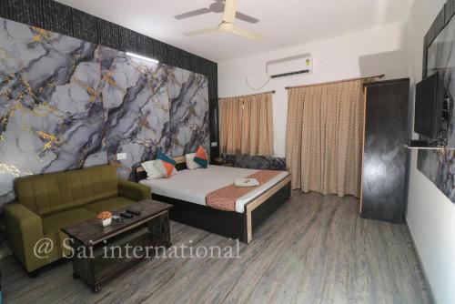 a room with a bed and a couch and a tv at Sai International Guest House in kolkata