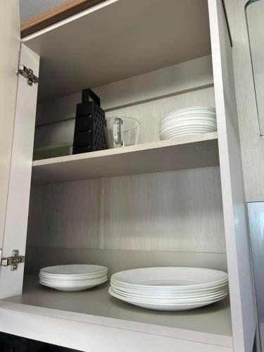a cabinet filled with white plates and dishes at haven kent coast in Allhallows