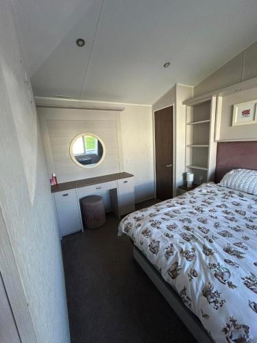 a bedroom with a bed and a desk and a mirror at haven kent coast in Allhallows