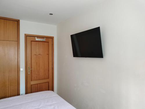 a bedroom with a bed and a flat screen tv on the wall at Rooms São Dinis in Porto