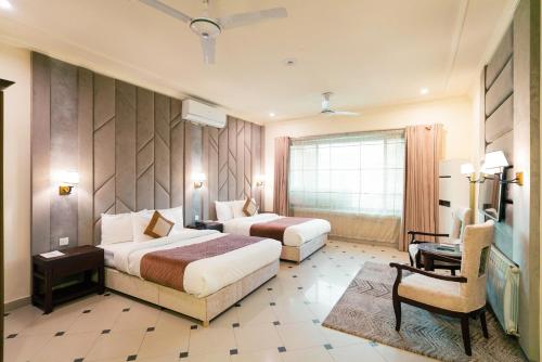 a hotel room with two beds and a chair at Shelton Rezidor House F-8 Islamabad in Islamabad