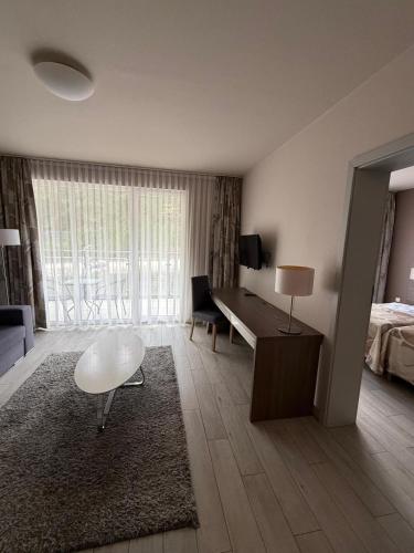 a living room with a bed and a desk with a table at Apartament Rajka in Biała Woda