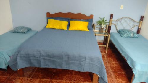 a bedroom with two beds with yellow and blue pillows at Casarao dos Reis in Mosqueiro