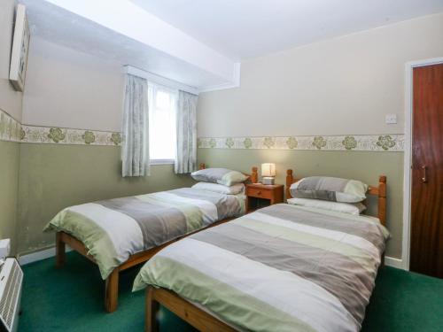 a room with three beds and a window at First Floor Apartment in Porthmadog