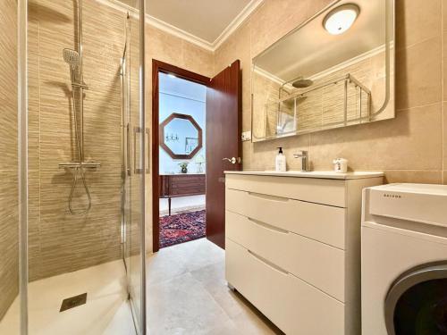 a bathroom with a shower and a sink and a washing machine at La Luz de La Concha in Suances