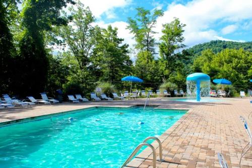 a swimming pool with blue umbrellas and chairs at Arcade game, hottub, dog friendly 2 bedroom log cabin in Gatlinburg near Ober and the national park! in Gatlinburg