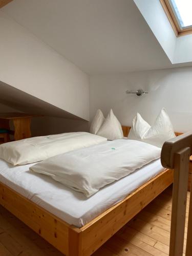 a bed with white sheets and pillows in a room at Fichtenblockhütte in Sonnenalpe Nassfeld