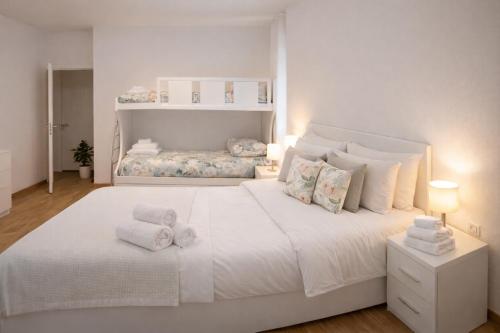 a white bedroom with a large white bed with towels on it at Valtellinaresidence in Sondrio