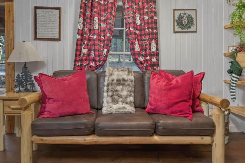 a brown couch with red pillows in a living room at Summer Breeze cabin at Cabin Fever in NC in Saluda