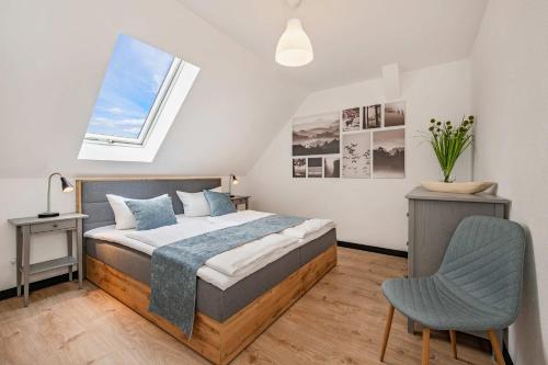 a bedroom with a bed and a chair and a window at FeWo Dock12C in Kölpinsee