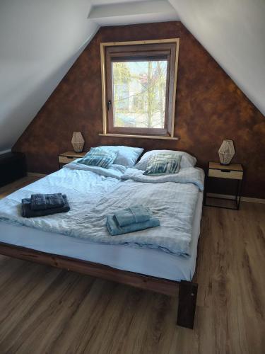 a bedroom with a bed with two pillows and a window at Domek Brzozowa Kropelka in Dąbrówno