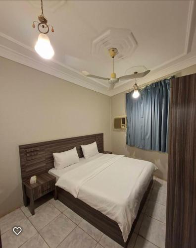 a bedroom with a large bed with white sheets at company petty bark شركة بيتي بارك للشقق المخدومة درجة اقصادية in Qarār