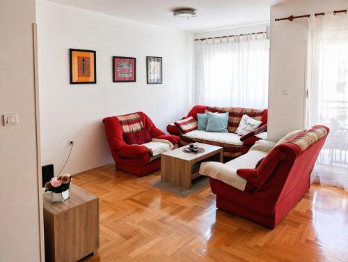 a living room with two red couches and a table at Studio Centar in Trebinje