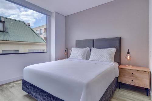 a white bedroom with a large bed and a window at Hotel EspacioYa By Mario Rental 103 in Bogotá