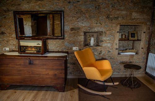 an orange chair in a room with a stone wall at O rincón de Agrón in Melide
