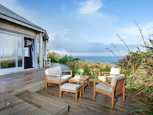 a wooden deck with chairs and a table with a view of the ocean at Shark Fin in Sennen