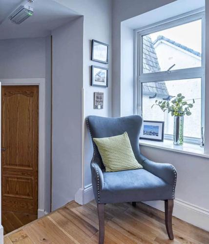 a blue chair sitting in a room with a window at Charming & Cosy Drymen Flat in Drymen