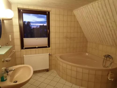 a bathroom with a tub and a sink and a window at Apartments Achterblick in Ueckeritz