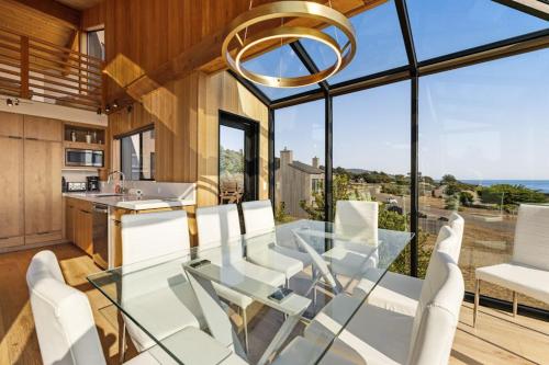 a dining room with a glass table and white chairs at Breakers Retreat in Sea Ranch