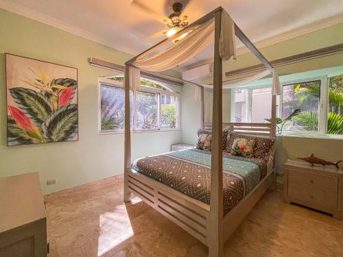 a bedroom with a canopy bed and two windows at 1 min walk beach,bars,grocery in Punta Cana