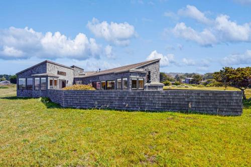 a brick house in a field with a grass field at Windrow Retreat in Sea Ranch