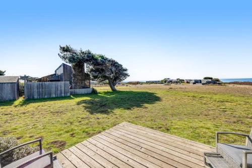 a wooden deck with a tree in a field at Samson Getaway in Sea Ranch