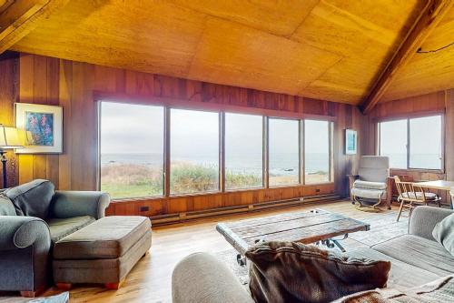 a living room with a table and some chairs and windows at Comstock Retreat in Sea Ranch