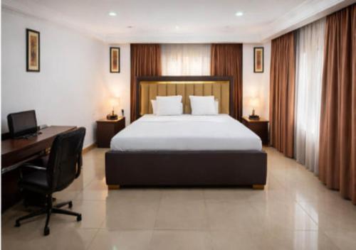 a bedroom with a bed and a desk and a computer at The Savannah Hotel, Garki in Abuja