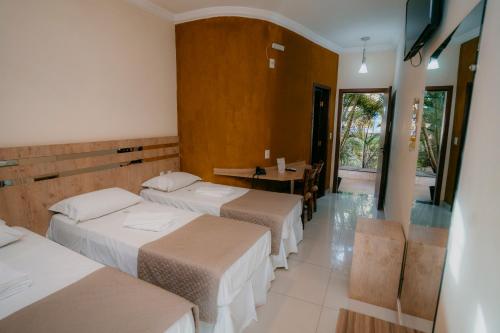 a hotel room with three beds and a table at Estrada Real Palace Hotel in Brumadinho