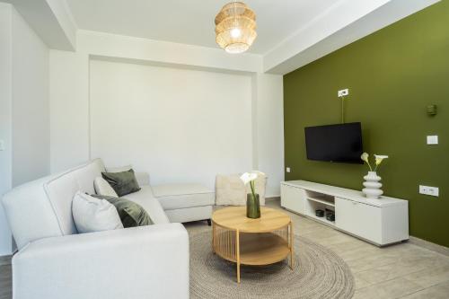 a living room with a white couch and a tv at Destinys Village I in Zakynthos