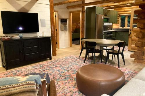 a living room with a table and a tv and a kitchen at Cabin Fever in Gualala