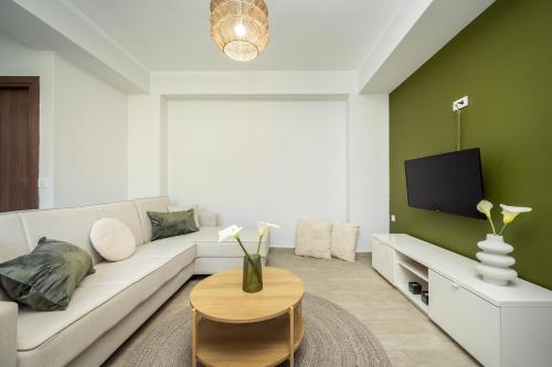 a living room with a white couch and a tv at Destinys Village I in Zakynthos