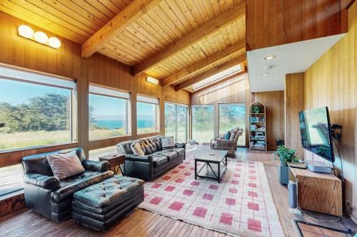 a living room with couches and a tv and windows at Albatross Reach in Sea Ranch