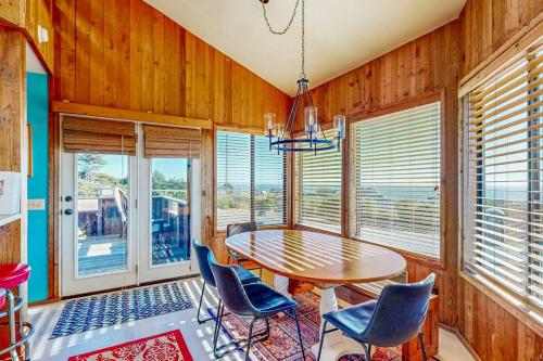a dining room with a table and chairs and windows at Clemons' Cottage in Sea Ranch