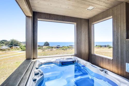 a hot tub in a room with two windows at Ascona House in Sea Ranch