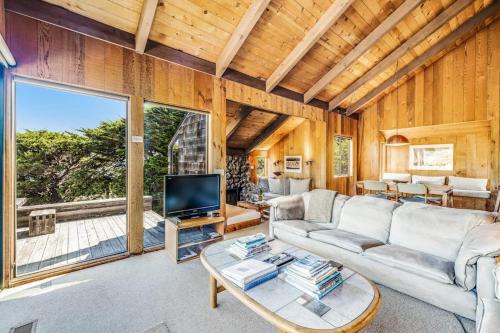 a living room with a couch and a tv at The Glass House in Sea Ranch
