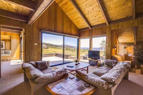 a living room with two couches and a table at The Glass House in Sea Ranch