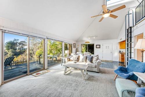 a living room with a ceiling fan and large windows at Cove House in Gualala