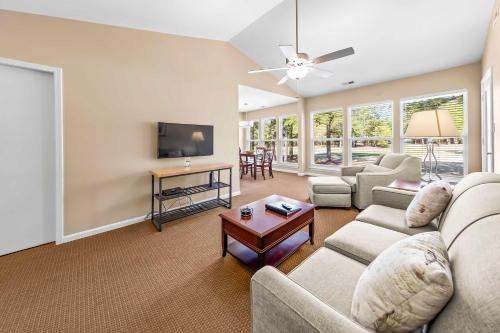 a living room with a couch and a tv at Luxury Condo with Golf Course Views Pools & Resort Access in New Bern