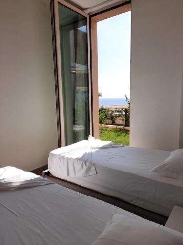two beds in a room with a large window at Sea La Sun, Green Coast in Palasë