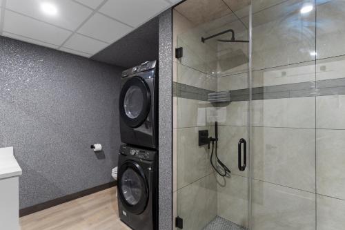 a bathroom with a shower and a washer and dryer at Lux Suites Extended Stay in Thunder Bay