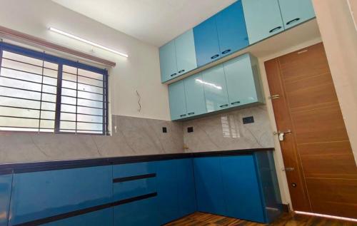 a kitchen with blue cabinets and a large window at Sheetal Service Apartment in Mangalore
