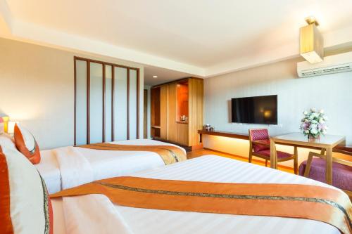 a hotel room with two beds and a television at Asia Hotels Group (Poonpetch Chiangmai) in Chiang Mai