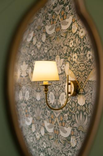 a lamp on a wall with a floral wallpaper at House Arundel in Arundel